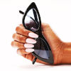 Hand met gelakt nagels die zonnebril vasthoudt